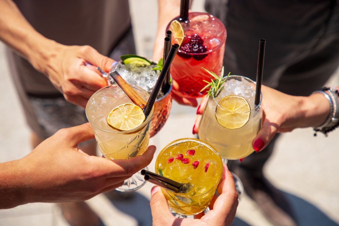 Freunde stoßen mit bunten Cocktails an