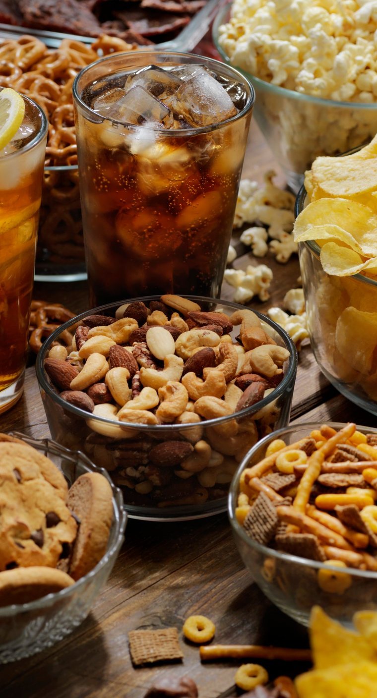 Drinks, Nüsse, Chips und Gebäck auf einem Holztisch